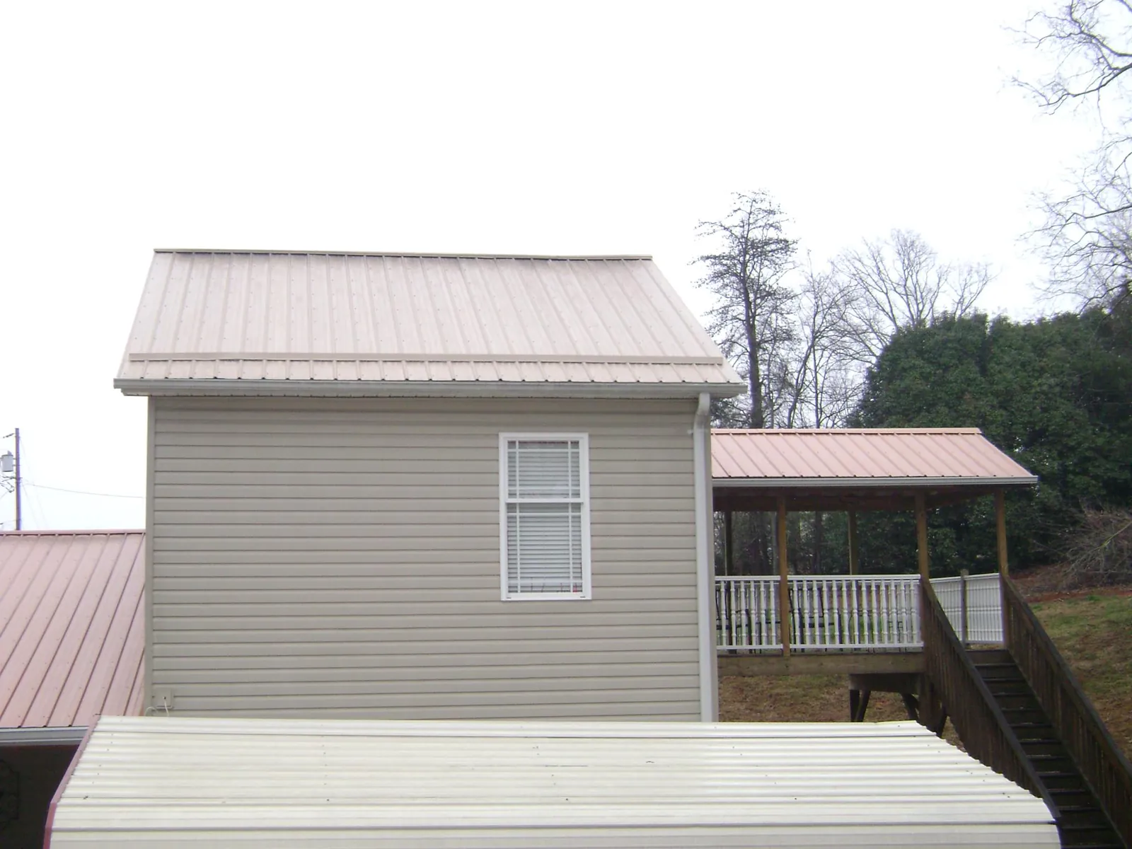 Tan metal roofs on a two story addition and attached porch, from a Roof Replacement job in Wheatland